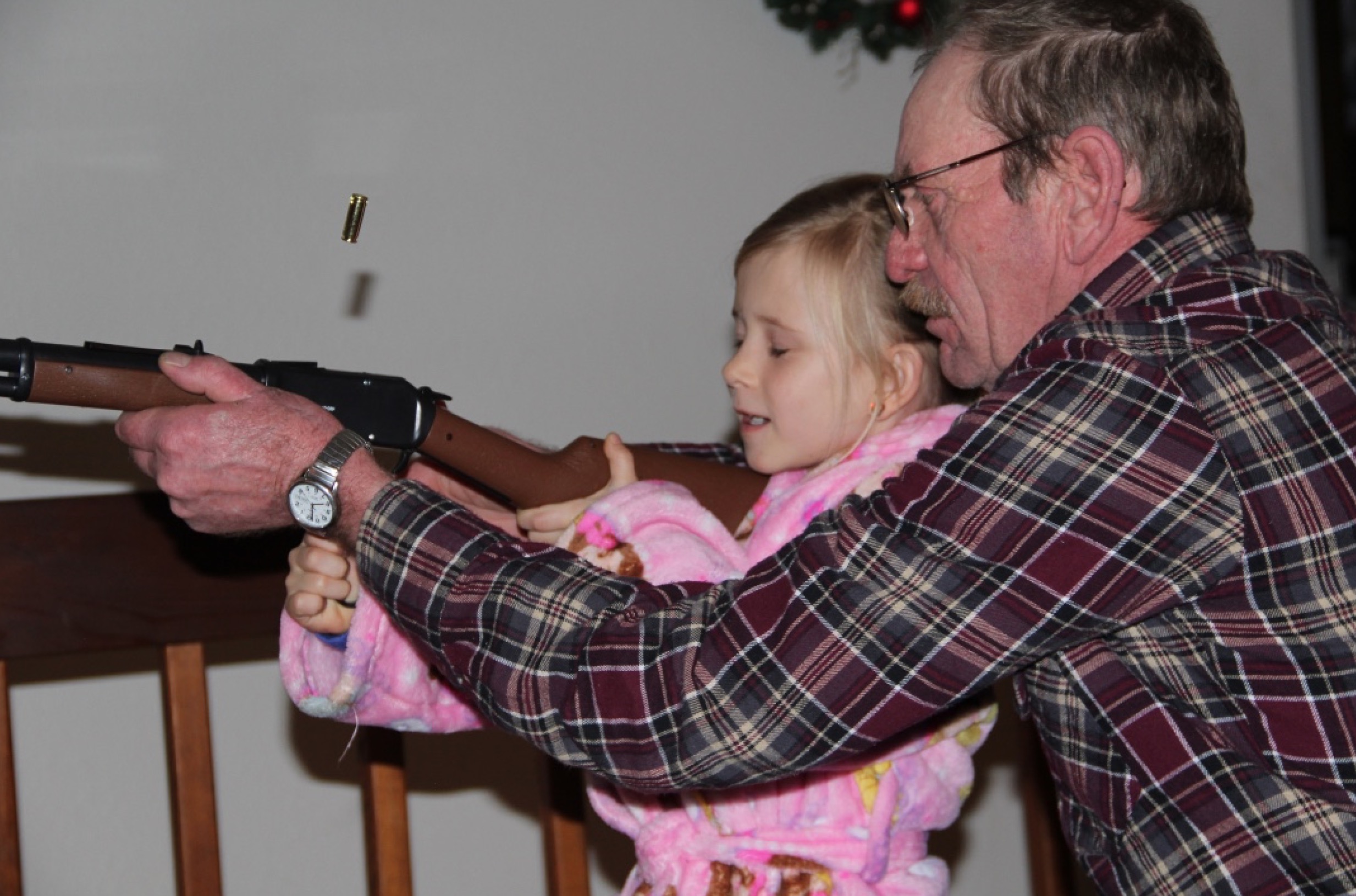 Grandpa showing Ellie how to shoot her toy gun while wearing her new robe.